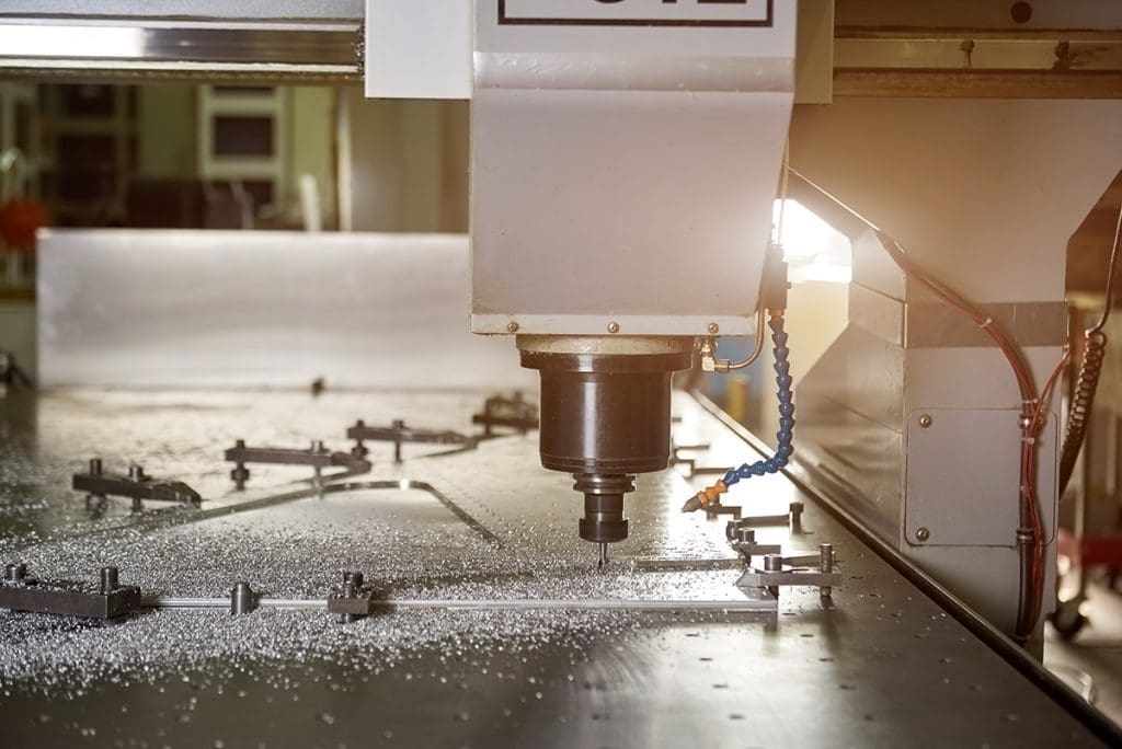A CNC drill in the process of drilling holes through a large piece of sheet metal